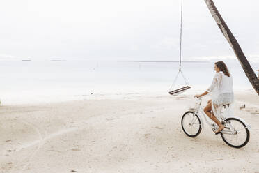 Frau fährt Fahrrad am Strand, Insel Maguhdhuvaa, Gaafu Dhaalu Atoll, Malediven - DAWF01237