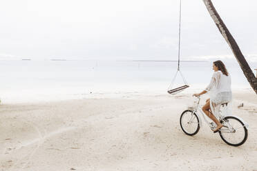 Woman riding bicycle on the beach, Maguhdhuvaa Island, Gaafu Dhaalu Atoll, Maldives - DAWF01237