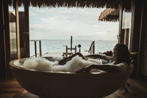 Frau entspannt sich in der Badewanne mit Blick auf das Meer, Insel Maguhdhuvaa, Gaafu Dhaalu Atoll, Malediven - DAWF01251