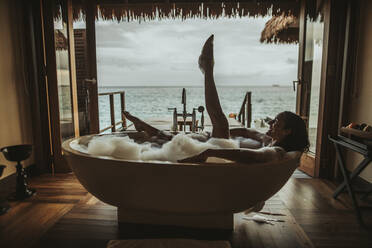 Frau entspannt sich in der Badewanne mit Blick auf das Meer, Insel Maguhdhuvaa, Gaafu Dhaalu Atoll, Malediven - DAWF01252