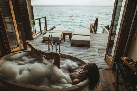 Frau entspannt sich in der Badewanne mit Blick auf das Meer, Insel Maguhdhuvaa, Gaafu Dhaalu Atoll, Malediven, lizenzfreies Stockfoto