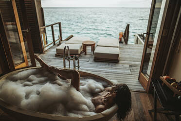 Woman relaxing in bathtub with view to the sea, Maguhdhuvaa Island, Gaafu Dhaalu Atoll, Maldives - DAWF01253