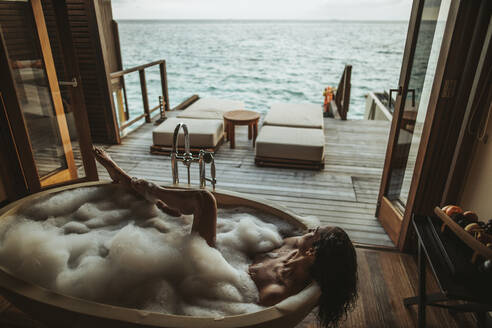 Frau entspannt sich in der Badewanne mit Blick auf das Meer, Insel Maguhdhuvaa, Gaafu Dhaalu Atoll, Malediven - DAWF01253