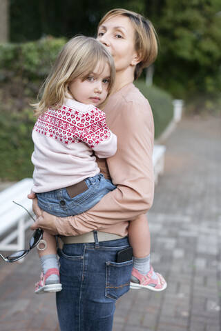 Porträt eines kleinen Mädchens in den Armen der Mutter, lizenzfreies Stockfoto