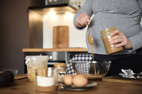 Schwangere Frau macht gesunden Kuchen mit Tahini, Walnüssen und dunkler Schokolade zu Hause, lizenzfreies Stockfoto