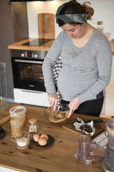 Schwangere Frau macht gesunden Kuchen mit Tahini, Walnüssen und dunkler Schokolade zu Hause - BZF00514