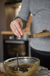 Schwangere Frau macht gesunden Kuchen mit Tahini, Walnüssen und dunkler Schokolade zu Hause - BZF00515