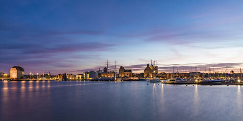 Germany, Mecklenburg-Western Pomerania, Stralsund, Panorama of illuminated waterfront of coastal town at dusk - WDF05746