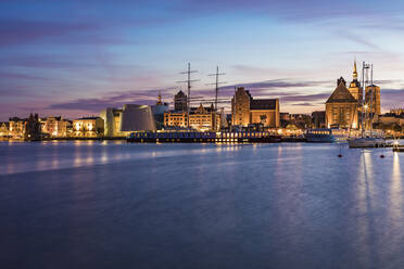 Deutschland, Mecklenburg-Vorpommern, Stralsund, Uferpromenade der Küstenstadt in der Abenddämmerung mit Segelschiff und Ozeaneum im Hintergrund - WDF05747