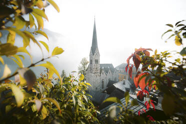 Österreich, Salzkammergut, Hallstatt Kirche im Nebel bei Sonnenaufgang - JRAF00003