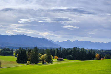 Deutschland, Bayern, Wildsteig, Wolken über Hütten am Rande eines Bergwaldes mit den Ammergauer Alpen im Hintergrund - LBF02865