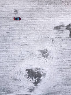Russland, Moskauer Gebiet, Luftaufnahme eines Autos auf einem schneebedeckten Feld - KNTF04146