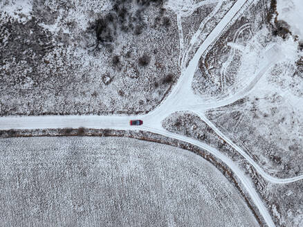 Russland, Moskauer Gebiet, Luftaufnahme eines Autos, das auf einer Landstraße an schneebedeckten Feldern vorbeifährt - KNTF04148