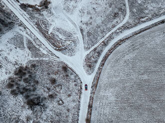 Russland, Moskauer Gebiet, Luftaufnahme eines Autos, das auf einer Landstraße an schneebedeckten Feldern vorbeifährt - KNTF04149