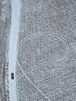 Russland, Moskauer Gebiet, Luftaufnahme eines Autos, das auf einer Landstraße an schneebedeckten Feldern vorbeifährt - KNTF04153