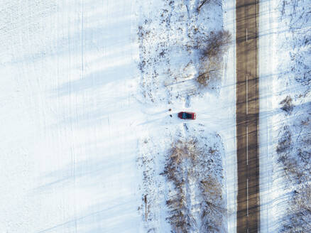 Russland, Gebiet Moskau, Luftaufnahme eines Autos, das in ein schneebedecktes Feld fährt - KNTF04154