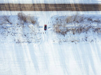 Russland, Gebiet Moskau, Luftaufnahme eines Autos, das in ein schneebedecktes Feld fährt - KNTF04155