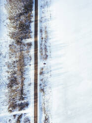 Russland, Gebiet Moskau, Luftaufnahme eines Autos, das in ein schneebedecktes Feld fährt - KNTF04157