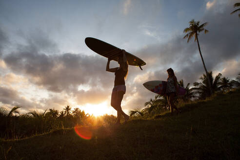 Zwei Frauen mit Surfbrettern auf einem Hügel bei Sonnenuntergang auf der Insel Siargao, Philippinen - FAF00084