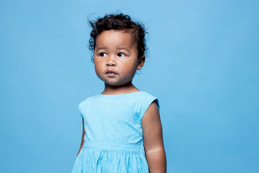 Porträt eines kleinen Mädchens mit hellblauem Kleid vor blauem Hintergrund - DAWF01264