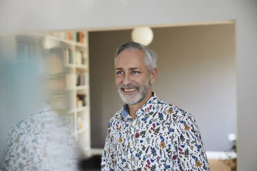 Porträt eines lächelnden reifen Mannes mit gemustertem Hemd zu Hause - FMKF06098
