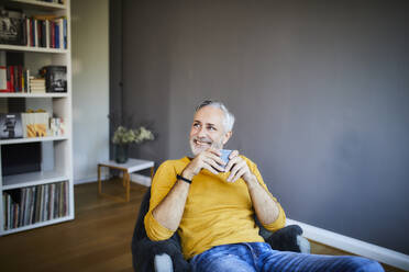Smiling relaxed mature man at home with cup of coffee - FMKF06107