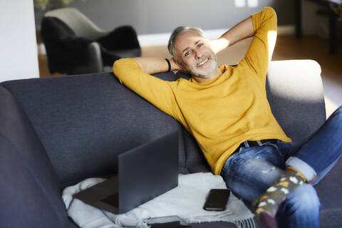 Portrait of smiling mature man relaxing at home stock photo