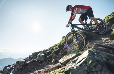 Mountainbiker beim Mountainbiken gegen die Sonne in Graubünden, Schweiz - HBIF00006
