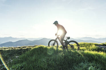 Mountainbiker gegen die Sonne auf einem Weg in Graubünden, Schweiz - HBIF00013