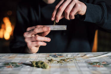 Nahaufnahme der Hände eines Mannes, der einen Marihuana-Joint vorbereitet - ACPF00675