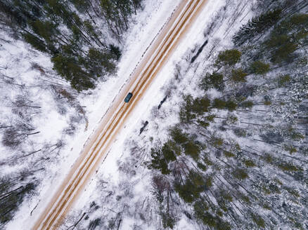 Russland, Leningrader Gebiet, Luftaufnahme einer Straße durch einen Wald im Winter - KNTF04165