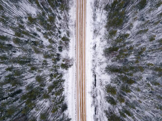 Russland, Leningrader Gebiet, Luftaufnahme einer Straße durch einen Wald im Winter - KNTF04166