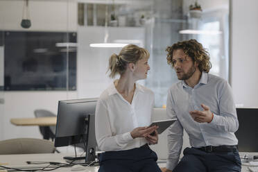 Businessman and businesswoman with tablet talking in offce - KNSF07482