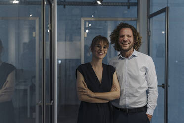 Portrait of happy businessman and businesswoman in office - KNSF07509