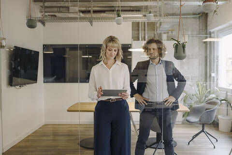 Businessman and businesswoman using tablet in office stock photo