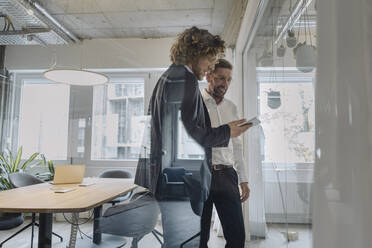 Two businessmen sharing tablet in office - KNSF07527