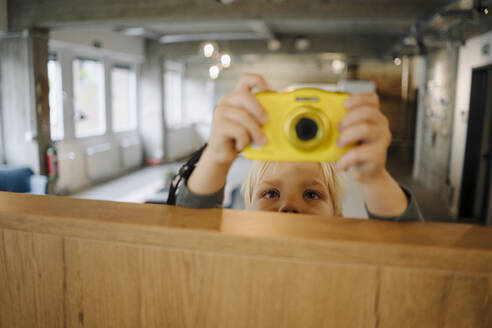 Junge, der ein Foto mit einer Kamera im Büro macht - KNSF07544