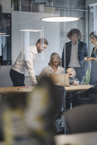 Business team with boy looking at laptop in office stock photo