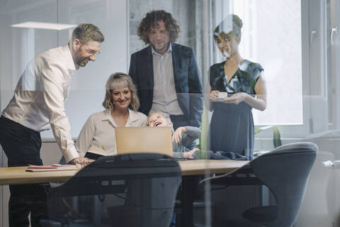 Business team with boy looking at laptop in office stock photo