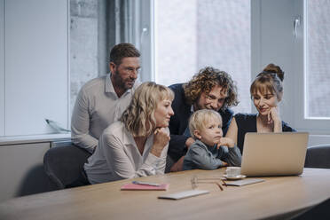 Geschäftsteam mit einem Jungen, der im Büro auf einen Laptop schaut - KNSF07574