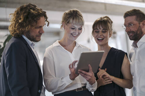 Happy business team having a meeting in office sharing a tablet - KNSF07577