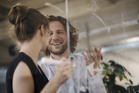 Lächelnder Geschäftsmann und Geschäftsfrau arbeiten an einem Projekt im Büro, lizenzfreies Stockfoto