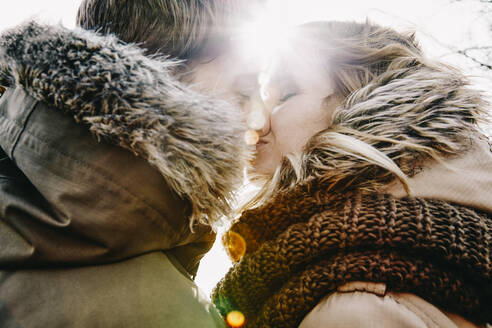 Küssendes junges Paar im Winter bei Gegenlicht - ANHF00148