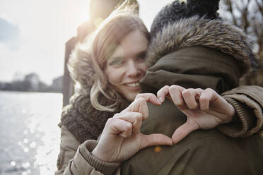 Happy young woman forming heart with her hands - ANHF00150