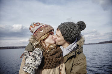 Young couple kissing in front of a lake - ANHF00160