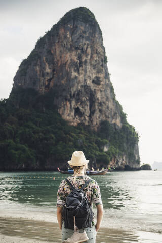 Frau betrachtet einen Felsen am Strand von Railay, Krabi, Thailand, lizenzfreies Stockfoto