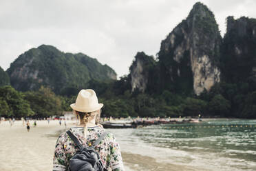 Frau betrachtet einen Felsen am Strand von Railay, Krabi, Thailand - CHPF00613