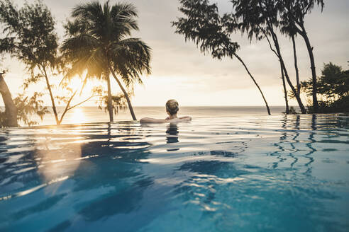 Rückansicht einer Frau im Infinity-Pool bei Sonnenuntergang, Nai Thon Beach, Phuket, Thailand - CHPF00619