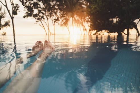 Beine einer Frau im Infinity-Pool bei Sonnenuntergang, Nai Thon Beach, Phuket, Thailand - CHPF00620