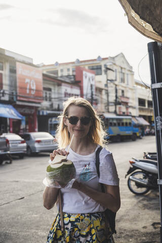 Portrait of smiling woman drinking from coconut, Old Town Phuket, Thailand stock photo